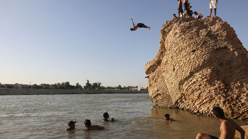 An Iraqi dives into the waters of the Tigris river in Baghdad on July 12, 2023, as temperatures soared past 45 degrees Celsius