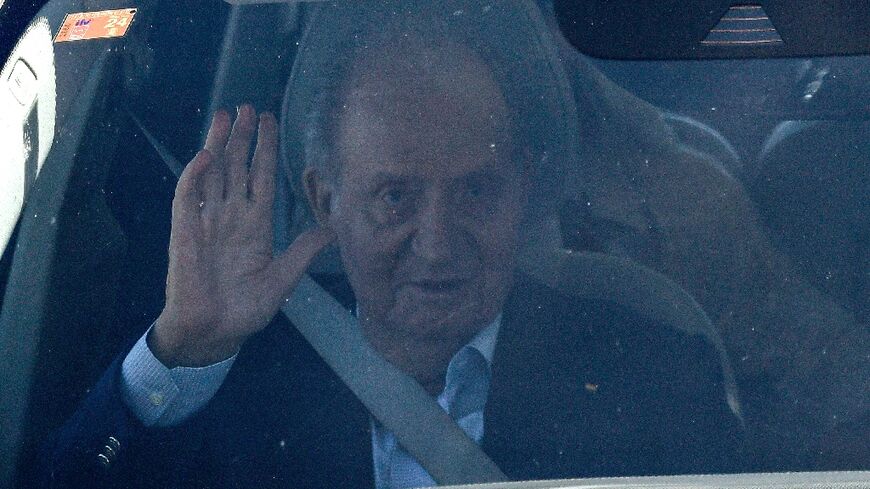 Spain's former King Juan Carlos waves in a car upon his arrival in Vigo airport