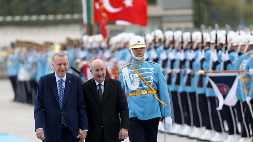 Turkish President Recep Tayyip Erdogan (L) and his Algerian counterpart Abdelmadjid Tebboune (C) review a military honour guard hand-in-hand during a arrival ceremony, in Ankara, on May 16, 2022. (Photo by Adem ALTAN / AFP) (Photo by ADEM ALTAN/AFP via Getty Images)