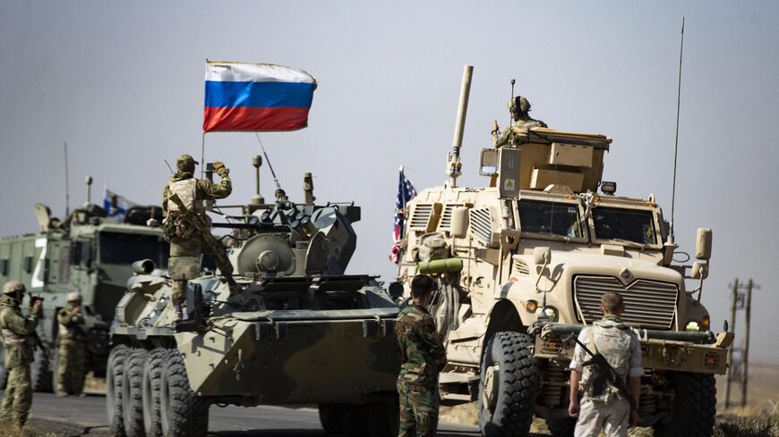Soldiers of a Russian military convoy and their US counterparts exchange greetings as their patrol routes intersect in an oil field near Syria's al-Qahtaniyah town in the northeastern Hasakah province, close to the border with Turkey, on Oct. 8, 2022. 