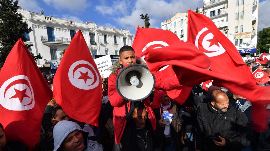Tunisian demonstrators raise national flags and protest placards as they take to the streets of the capital Tunis, on January 14, 2023, to protest against their president. - In July 2021, President Kais Saied sacked the government, froze parliament and seized far-reaching executive powers, later grabbing control of the judiciary -- moves opponents said aimed to install a new dictatorship in the birthplace of the Arab Spring uprisings. (Photo by FETHI BELAID / AFP) (Photo by FETHI BELAID/AFP via Getty Images