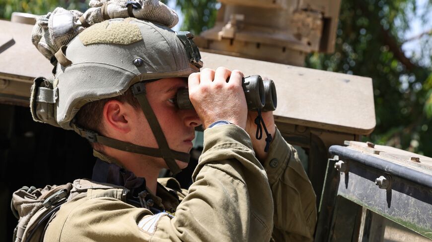 An Israeli soldier uses a binoculars during a patrol in the town of Ghajar in the annexed Golan Heights bordering Lebanon on July 6, 2023. The Israeli army said it was conducting strikes on southern Lebanon after a mortar launched from its northern neighbour exploded in the border area between the two foes. The latest military action was launched three months after the two countries saw their worst cross-border fire in years. (Photo by jalaa marey / AFP) (Photo by JALAA MAREY/AFP via Getty Images)