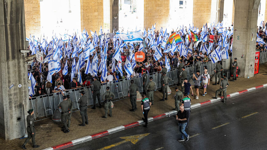 Israeli border guards stand alert as anti-government demonstrators rally with national and pride rainbow flags behind barriers during a protest at Ben Gurion Airport near Lod, July 11, 2023.