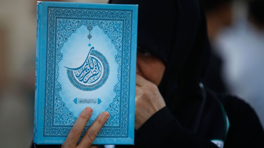 A supporter of the former paramilitary group Hashd al-Shaabi holds the Koran.
