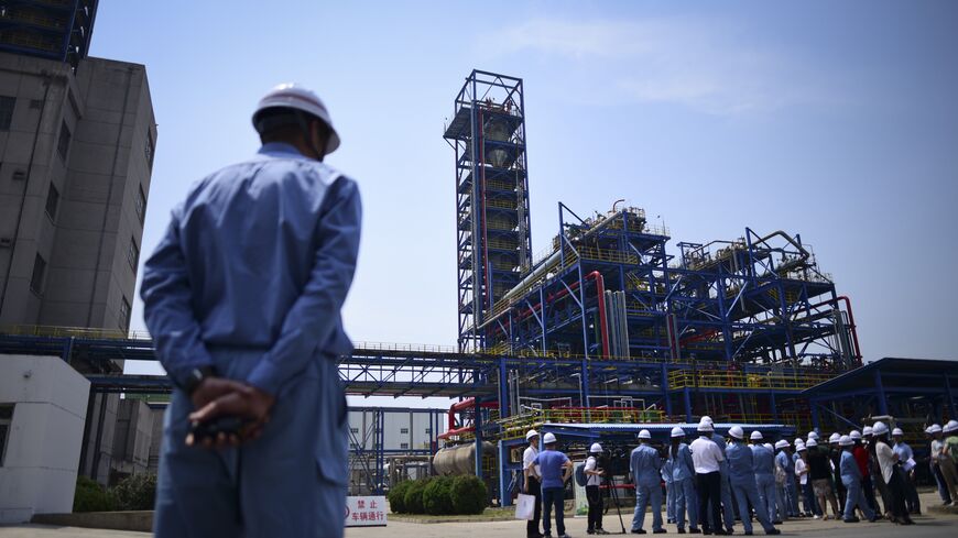 A Sinopec employee looks at a group of jounalists visiting Polypropylene Plant No3 of the Sinopec Yanshan Petrochemical Company (SYPC) during a tour arranged by the State Council Information Office in Beijing on May 25, 2018. (Photo by WANG Zhao / AFP) (Photo credit should read WANG ZHAO/AFP via Getty Images)