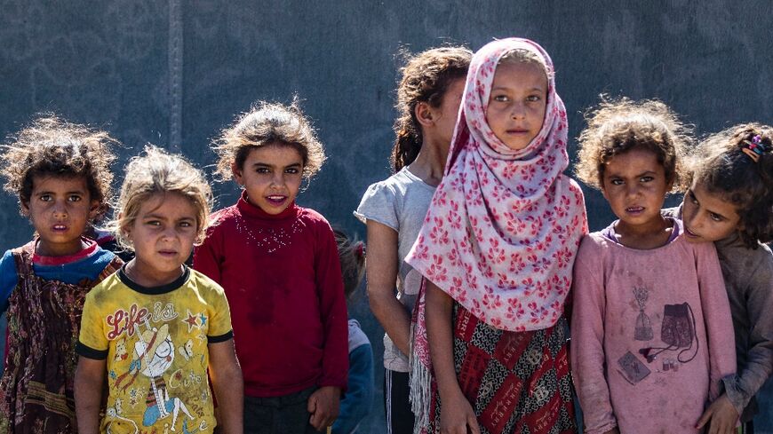 Girls stand next to a tent at the Al-Yunani makeshift camp in Syria's northern province of Raqa