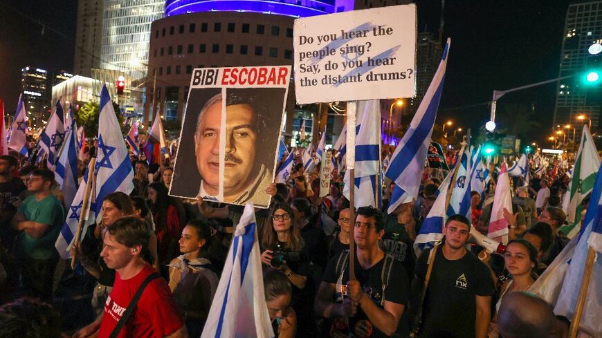 Israelis wave flags and lift placards during a demonstration in Tel Aviv against the government's judicial overhaul