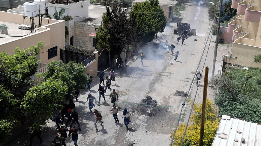 Palestinian protesters run for cover as Israeli forces fire teargas during clashes following a protest against a march by Israeli settlers to the wildcat settlement outpost of Homesh, in the village of Burqa, West Bank, April 19, 2022.