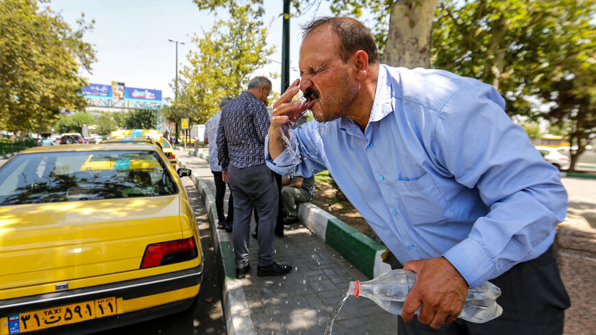 A man rinses his face with water from a bottle to cool off during a heat wave in Tehran on July 11, 2023. 