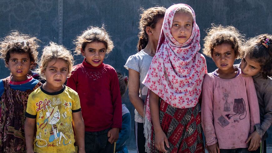 Girls stand next to a tent at the Al-Yunani makeshift camp for internally displaced people in Syria.