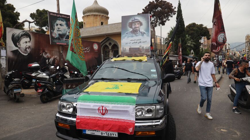 A vehicle displays the flags of Iran and the Lebanese Shiite movement Hezbollah as it moves in a funerary procession for a fallen fighter in Beirut's predominantly-Shiite Muslim southern suburb, on August 10, 2023 after he was killed the previous day amidst clashes between Hezbollah and residents of the Christian town of Kahale in Mount Lebanon. The Lebanese army said on August 10 that it had seized munitions from a Hezbollah truck that overturned near Beirut, leading to deadly clashes between Christian res