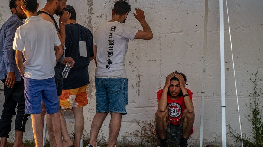 Survivors of the June shipwreck off the coast of Greece stand outside a warehouse at the port in Kalamata town
