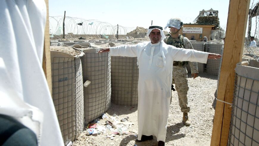 A US marine frisks an Iraqi man entering the Abu Ghraib prison to visit a relative in May 2004