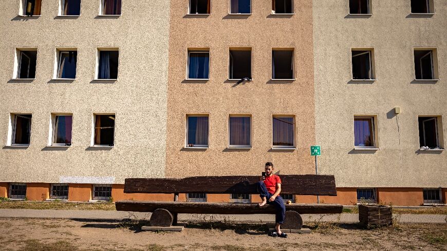 A resident sits on a bench in the courtyard between housing blocks at Brandenburg's Central Immigration Authority centre