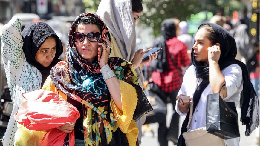 A woman speaks on a mobile phone while walking along a street in Tehran