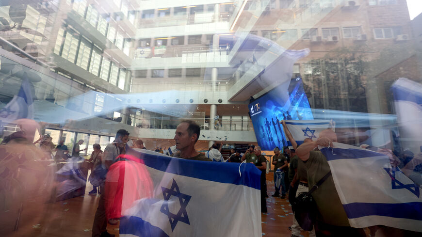 Demonstrators lift flags during a protest against the Israeli government's judicial overhaul bill, in front of the stock exchange complex in Tel Aviv on July 18, 2023. The proposals have divided the nation and triggered one of the biggest protest movements in Israel's history since being unveiled in January by the hard-right government of Prime Minister Benjamin Netanyahu. (Photo by Menahem KAHANA / AFP) (Photo by MENAHEM KAHANA/AFP via Getty Images)