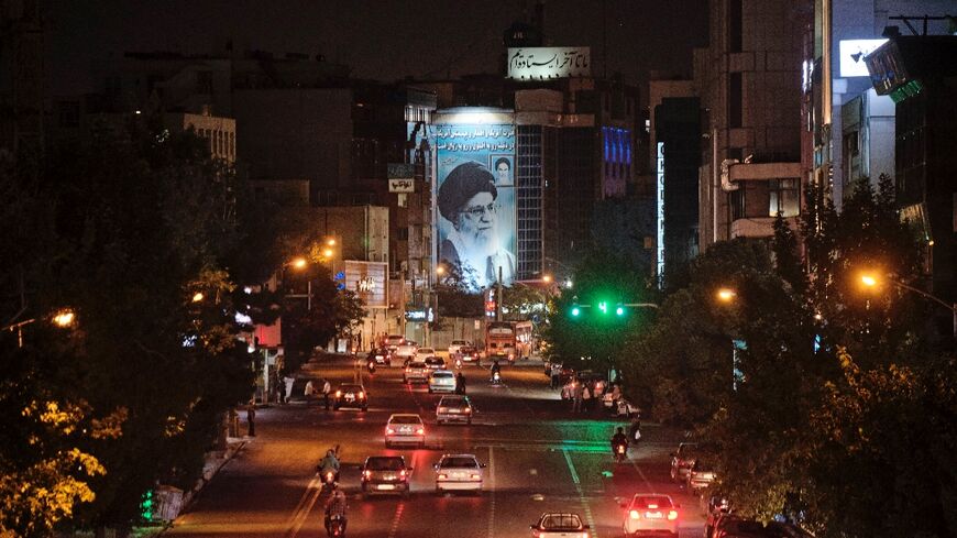 A banner depicting Iran’s Supreme Leader Ayatollah Ali Khamenei is illuminated in downtown Tehran  on June 20, 2021 