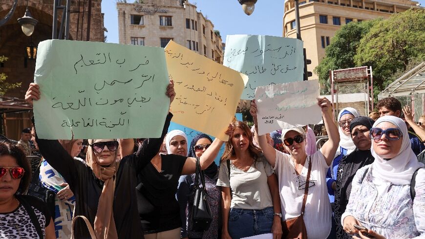 School teachers lift placards during a sit-in outside Lebanon's parliament protesting poor pay at public schools