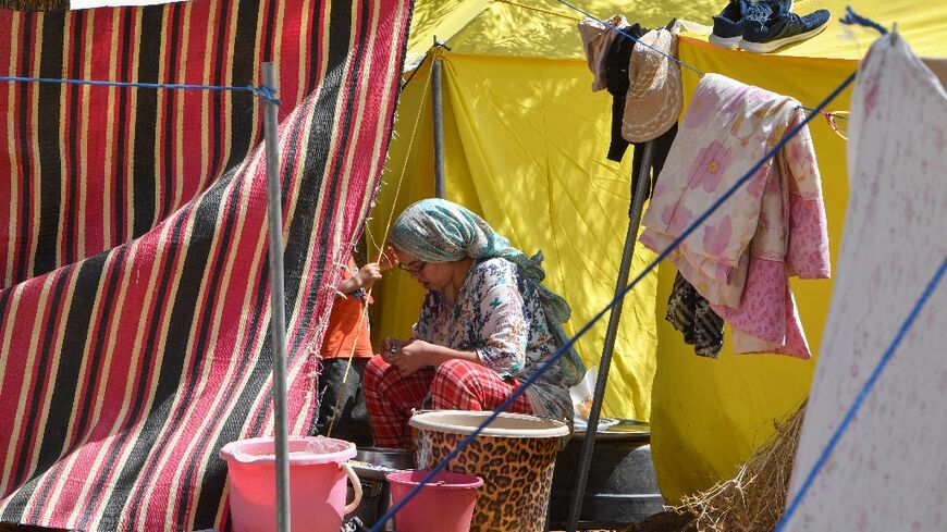 A woman sits outside her tent at a camp for locals displaced by a devastating earthquake in Amizmiz on September 16, 2023