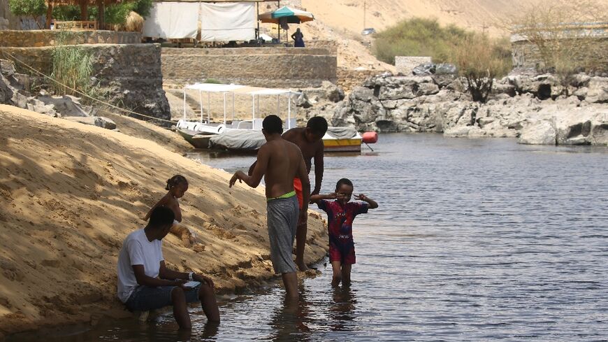 Sudanese who fled the war in their country cool off on the banks of the Nile river in the Egyptian city of Aswan