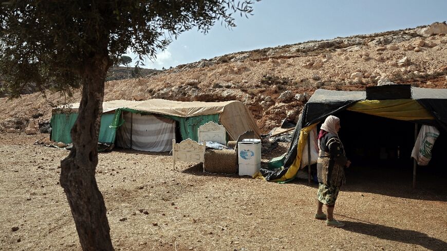 A woman from Wadi al-Seeq walks toward temporary shelters set up in the nearby town of Taybeh where the villagers have taken refuge after being thrown off their own lands