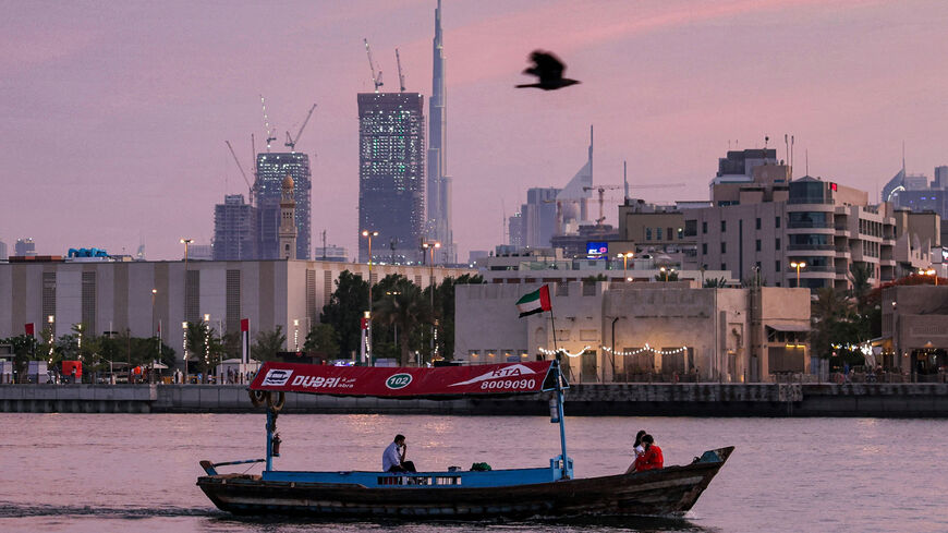 A bird flies past a boat sailing along Dubai creek in the Gulf emirate on May 2, 2021 while the Burj Khalifa skyscraper is seen in the background. (Photo by GIUSEPPE CACACE / AFP) (Photo by GIUSEPPE CACACE/AFP via Getty Images)