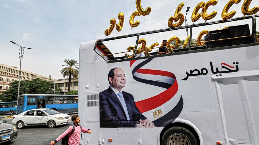 A school boy walks near an election campaign bus for Egypt's President Abdel Fattah al-Sisi adorned with his image, his slogan "long live Egypt", and C-shaped balloons, as Sisi's supporters prepare for a rally in Giza, the twin-city of the Egyptian capital, on October 2, 2023. (Photo by Khaled DESOUKI / AFP) (Photo by KHALED DESOUKI/AFP via Getty Images)