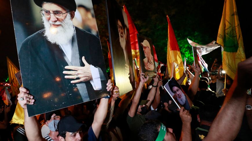 Iraqis hold portait of Iran's Supreme Leader Ayatollah Ali Khamenei (L) and shout slogans during a demonstration near the suspension bridge leading to Baghdad's Green Zone and the US Embassy in Baghdad on October 18, 2023, protesting a strike on a Gaza hospital which killed hundreds a day earlier. Thousands rallied across the Arab and Muslim world on October 18 to protest the deaths of hundreds of people in a strike on a Gaza hospital that they blame on Israel, despite its denials. (Photo by Ahmad AL-RUBAYE