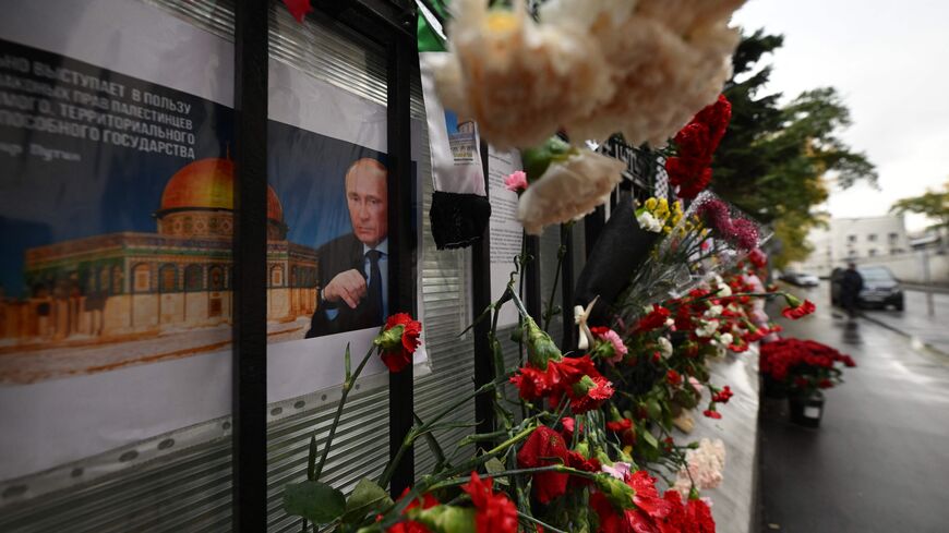 Floral tributes and a poster depicting Russian President Vladimir Putin are seen left at the fence of the Palestinian embassy in Moscow on October 19, 2023. Thousands of people, both Israeli and Palestinians have died since October 7, 2023, after Palestinian Hamas militants entered Israel in a surprise attack leading Israel to declare war on Hamas in the Gaza Strip on October 8. (Photo by Natalia KOLESNIKOVA / AFP) (Photo by NATALIA KOLESNIKOVA/AFP via Getty Images)