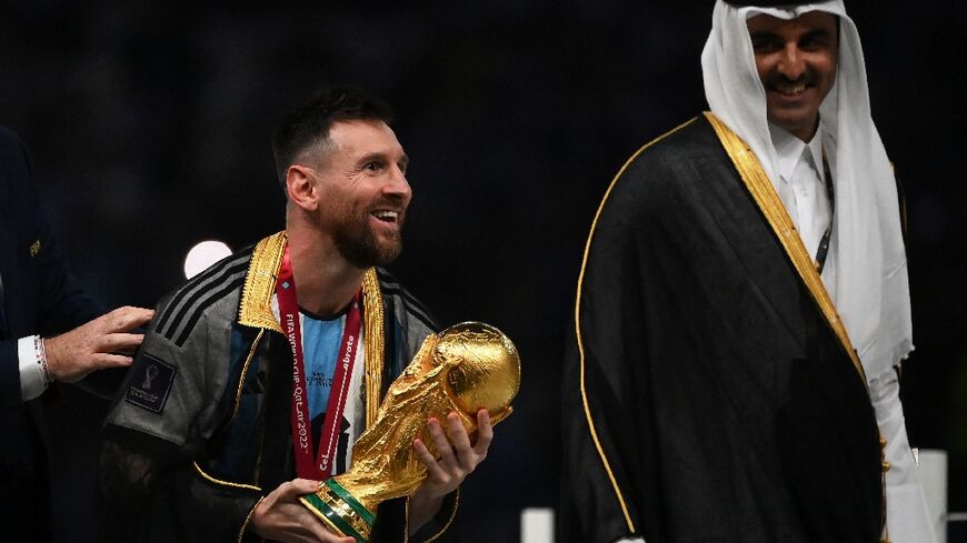 Lionel Messi holds the World Cup trophy next to Qatar's Emir Sheikh Tamim bin Hamad al-Thani after Argentina's victory in 2022