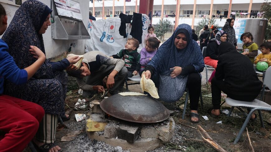 Palestinian women bake bread on a wood-burning stove in the grounds of a school in Rafah