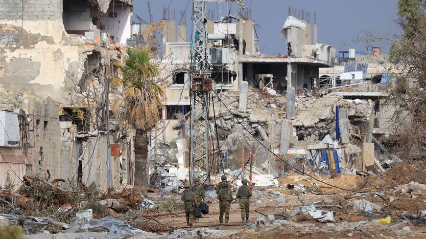 Israeli troops walk past destroyed buildings along the north-south Salaheddine road in Gaza