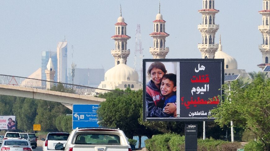 Cars drive past a billboard in Kuwait City showing Palestinian children and the slogan: "Have you killed a Palestinian today? #boycott"