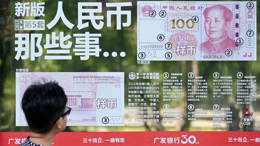 A woman looks at an instructional sticker on a bank door, showing how to distinguish genuine yuan banknotes from counterfeits, in Beijing on Aug. 16, 2019. 