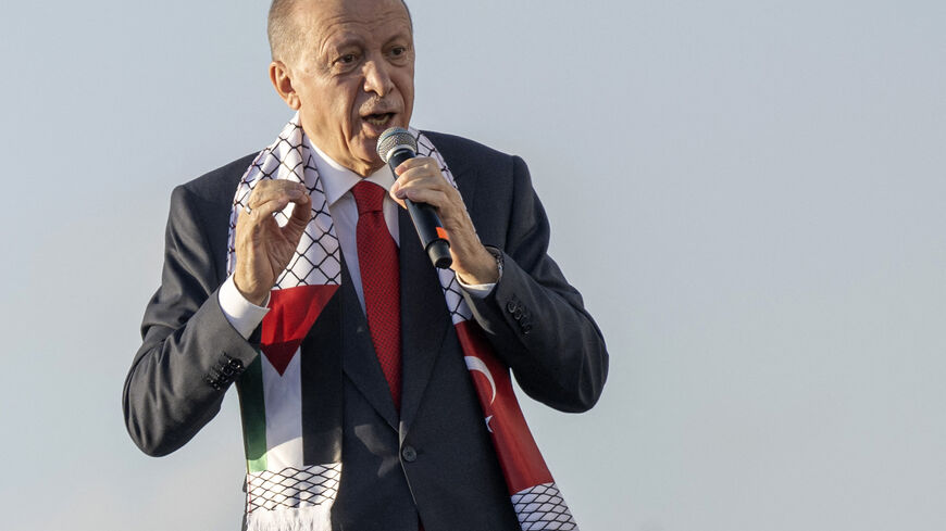Turkish President Recep Tayyip Erdogan wears a scarf with both Turkish and Palestinian flags as he addresses a rally organised by the AKP party in solidarity with the Palestinians in Gaza, in Istanbul on October 28, 2023.