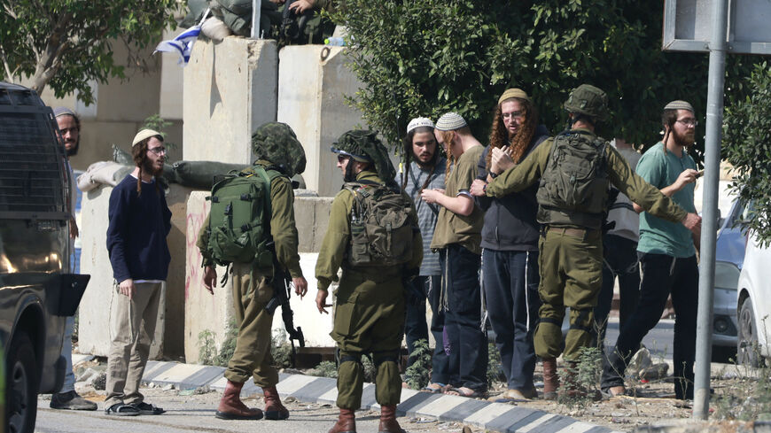 Israeli soldiers restrain Jewish settlers after they stormed the Palestinian West Bank village of Dayr Sharaf, located about four miles from the Jewish Einav settlement, following the death of an Israeli man on Nov. 2, 2023, amid the ongoing battles between Israel and the Palestinian group Hamas in the Gaza Strip.