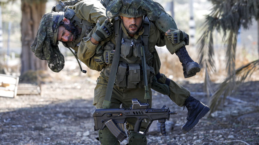 TOPSHOT - An Israeli soldier carries a comrade as they train while keeping a position in the upper Galilee region of northern Israel near the border with Lebanon on November 8, 2023, amid increasing cross-border tensions between Hezbollah and Israel as fighting continues in the south with Hamas militants in the Gaza Strip. (Photo by Jalaa MAREY / AFP) (Photo by JALAA MAREY/AFP via Getty Images)