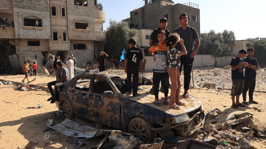 Palestinians stand on a destroyed vehicle as they watch rescuers search the debris of a building after an Israeli strike on Rafah, in the southern Gaza Strip on Nov. 9, 2023, amid the ongoing battles between Israel and the Palestinian group Hamas.