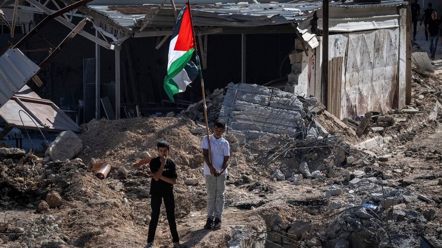 TOPSHOT - A young young boy raises a Palestinian flag as he stands with another amid the debris of a house damaged in an Israeli raid followed by clashes with Palestinians, in the occupied West Bank Jenin refugee camp on November 10, 2023. Israeli forces on November 9 killed 18 Palestinians across the occupied West Bank, the territory's health ministry said, most of them shot dead during an army raid on Jenin. (Photo by Aris MESSINIS / AFP) (Photo by ARIS MESSINIS/AFP via Getty Images)