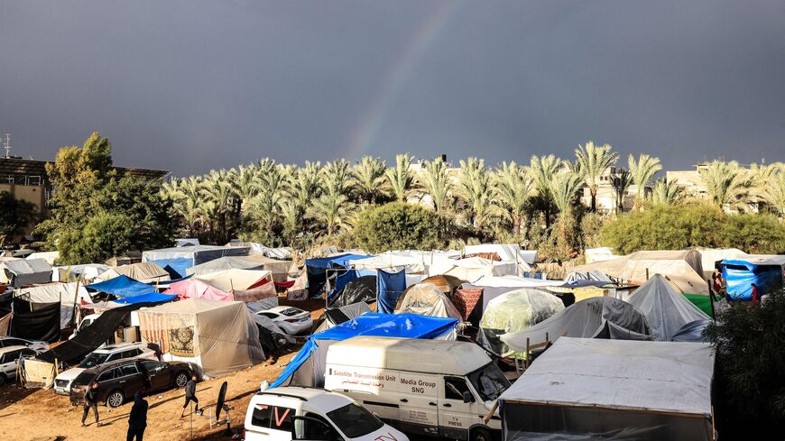 A rainbow appears across the sky as internally displaced Palestinians who fled the Israeli military bombardment and incursion into the northern Gaza Strip shelter in makeshift tents.