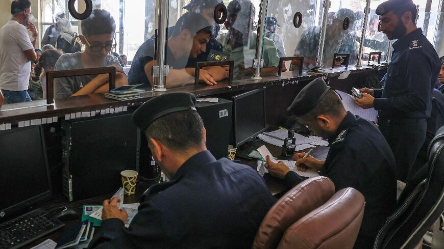 Civilians leaving Gaza display their documents as dual national Palestinians and foreigners prepare to cross the Rafah border with Egypt