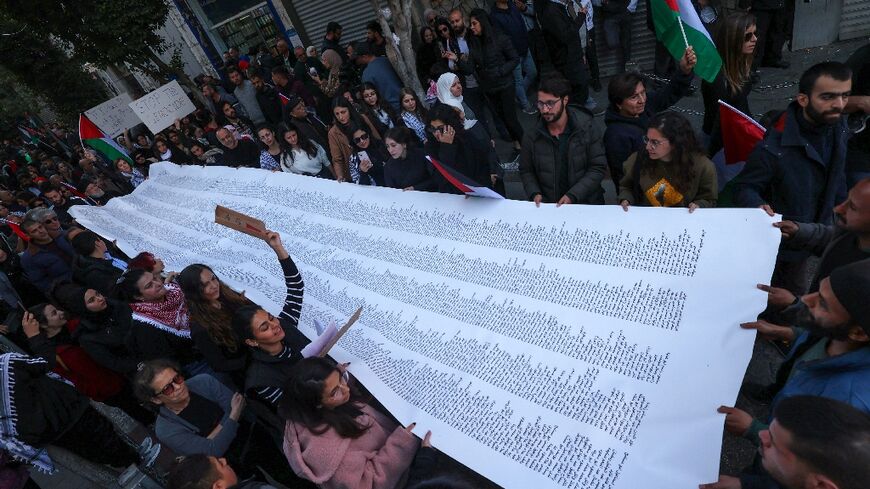 Palestinians carry a list of Gaza victims during a general strike rally in Ramallah, the occupied West Bank 