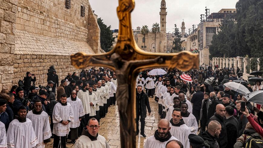 A crucifix is raised as deacons and other clergymen congregate for Christmas Eve celebrations outside the Church of the Nativity in the biblical city of Bethlehem in the occupied West Bank