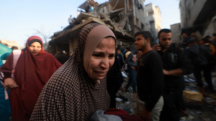 A Palestinian woman reacts as people check the rubble of a building destroyed in the Rafah refugee camp as Israeli air strikes resumed after a truce between Israel and Hamas militants expired