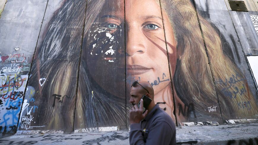 TOPSHOT - A man walks past a section of Israel's separation barrier painted with a portrait of Palestinian Ahed Tamimi, on November 6, 2023 in Bethlehem in the occupied West Bank. The Israeli army said on November 6 it had arrested the prominent 22-year-old Palestinian activist Ahed Tamimi during a raid in the occupied West Bank. (Photo by HAZEM BADER / AFP) (Photo by HAZEM BADER/AFP via Getty Images)