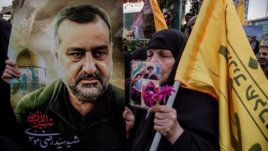  An Iranian woman holds a poster with a picture of Sayyed Razi Mousavi, commander of the Islamic Revolutionary Guard Corps in Syria, during his funeral ceremony at the Imam Hossein Square in Tehran, Dec. 28, 2023.