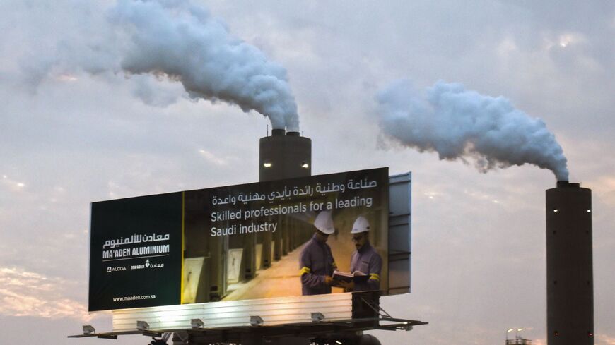 A picture taken on November 23, 2016 shows smoke plumes rising behind a billboard at the Maaden Aluminium Factory in Ras Al-Khair Industrial area near Jubail City, 570 kms east of the Saudi capital Riyadh. 