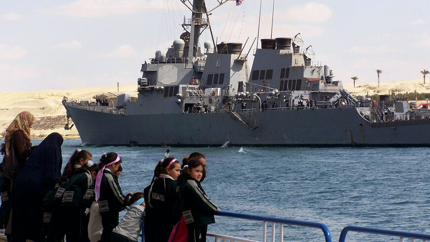 Egyptian school children stand on a pier in the port town of Ismalia, 120 kilometers northeast of Cairo, as the US guided-missile destroyer USS Mahan transits the Suez from the Red Sea towards the Mediterranean on its way back home after a six-month counter-piracy operation around the Gulf of Aden, Arabian Gulf, Indian Ocean and Red Sea. 