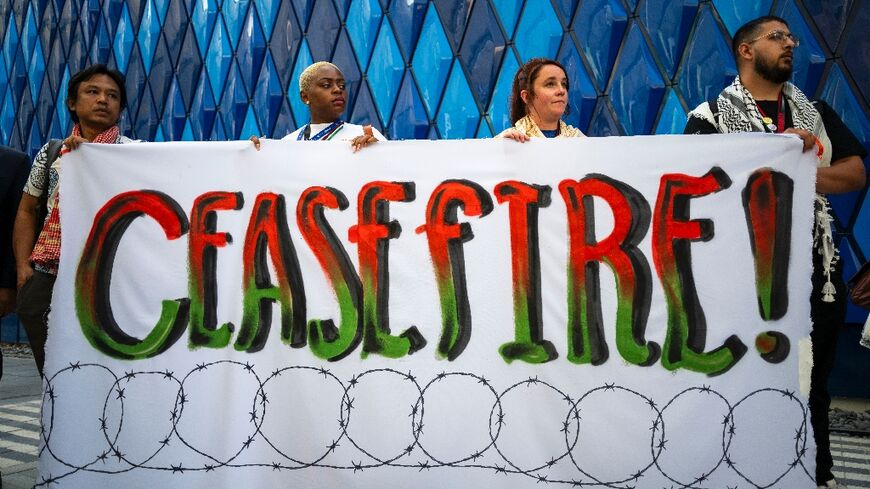 Activists at the COP28 summit display a banner during a demonstration demanding a ceasefire in the Israel-Hamas war