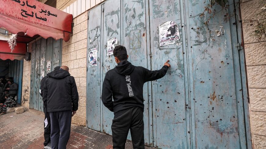 Palestinians inspect the bullet holes in the shutters of a shop in the West Bank town of Azzun after Israeli troops carried out a deadly raid